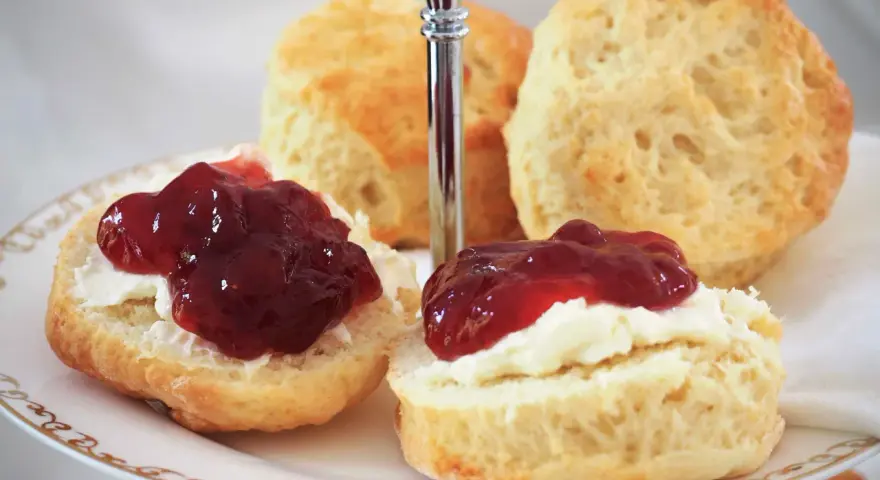 Zwei Scones mit Clotted Cream und Marmelade auf einer Etagere. Ein köstliches Rezept für Scones, perfekt für den Nachmittagstee.