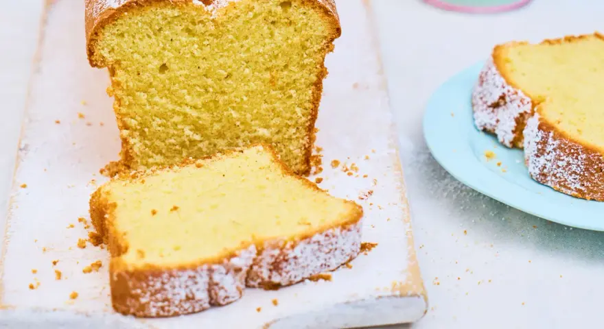 Ein saftiger Sandkuchen, bestäubt mit Puderzucker, wartet darauf, nach diesem einfachen Sandkuchen Rezept gebacken zu werden.