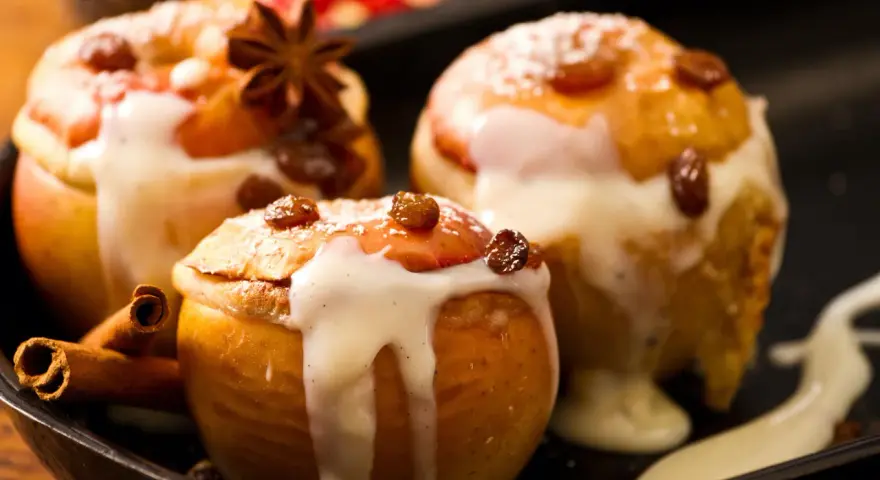 Drei köstliche Bratäpfel, übergossen mit Vanillesauce und garniert mit Rosinen und Zimtstangen. Ein perfektes Bratapfel Rezept für kalte Tage.