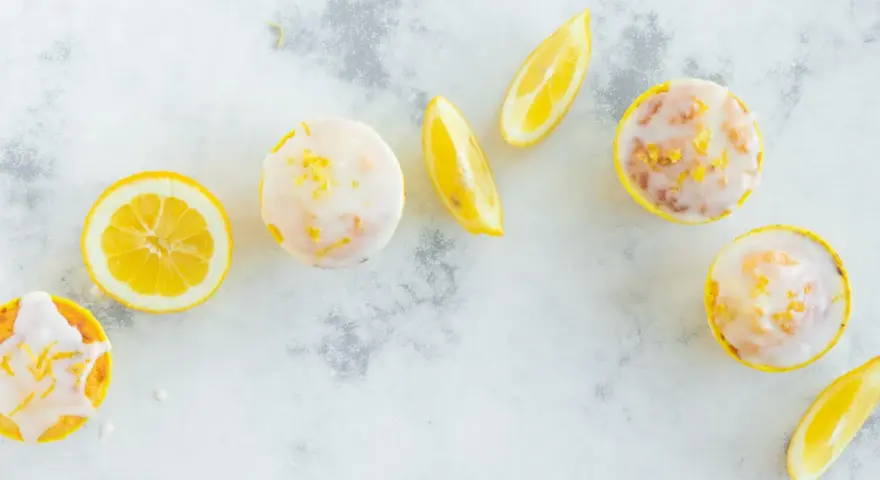 Erfrischende Zitronenmuffins mit Zuckerguss und Zitronenspalten. Ein tolles Rezept für zitronenmuffins!