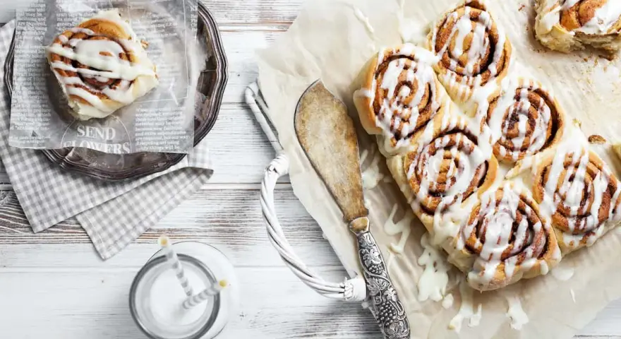Frisch gebackene schwedische Zimtschnecken mit Zuckerguss, serviert mit einem Glas Milch.