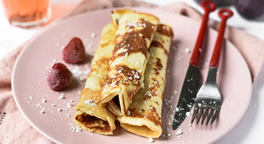 Gefüllte Pfannkuchen ohne Mehl, bestäubt mit Puderzucker, serviert mit Erdbeeren und Feigen.