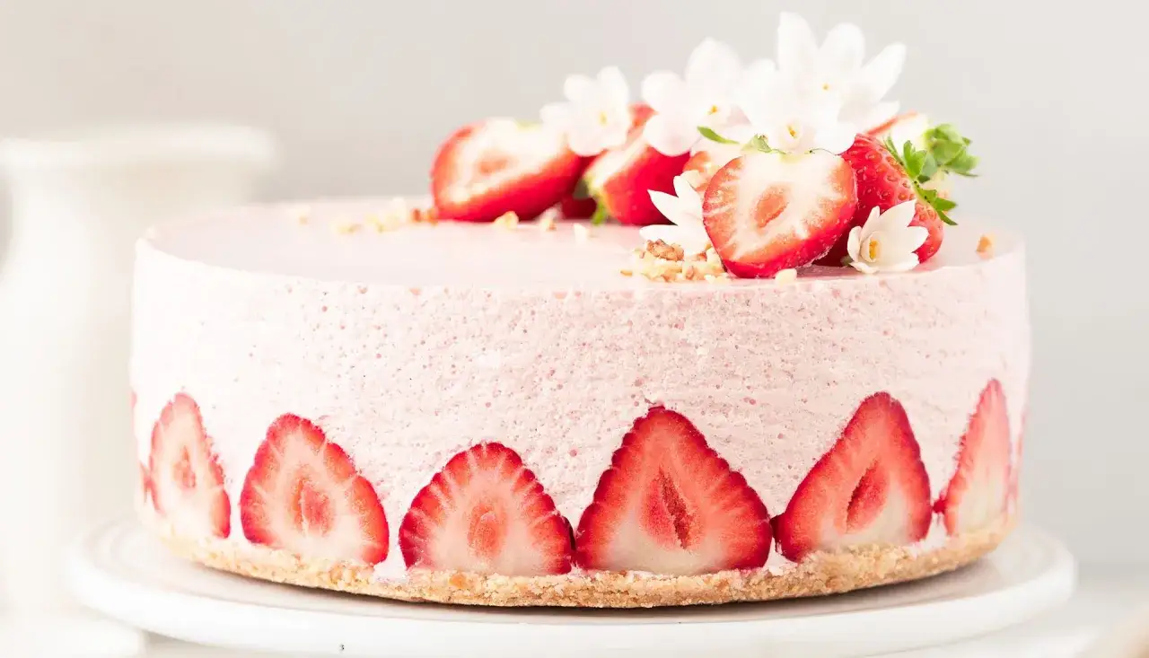 Ein zarter Erdbeer-Cheesecake, dekoriert mit frischen Erdbeerscheiben und kleinen wei&szlig;en Bl&uuml;ten.