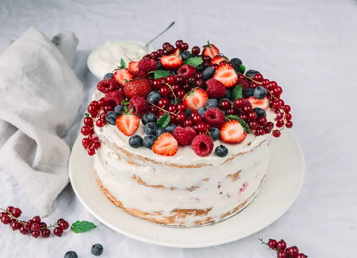 Himbeer Mascarpone Torte, üppig belegt mit frischen Beeren und Minze. Ein Genuss für Augen und Gaumen.