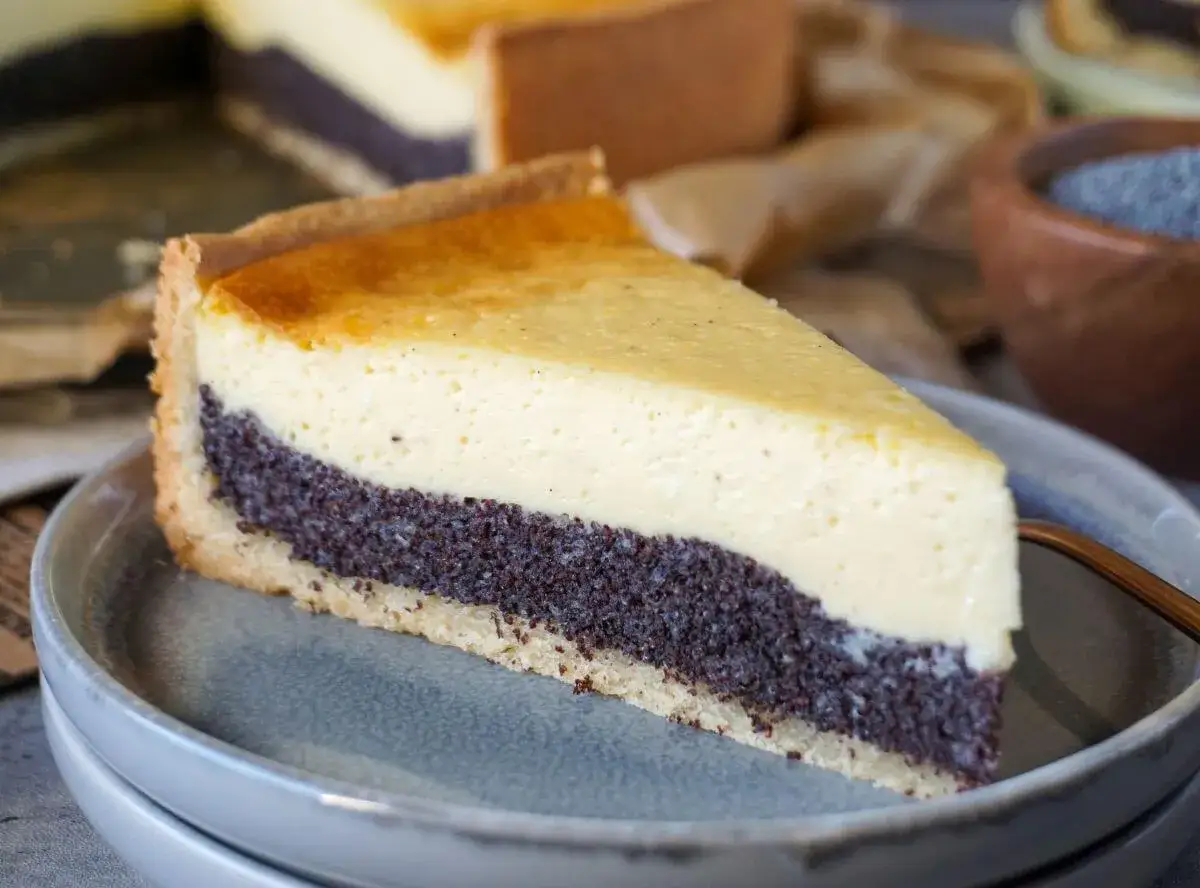 Ein St&uuml;ck saftiger Frau Holle Kuchen mit Mohnf&uuml;llung und cremiger K&auml;semasse auf einem grauen Teller.