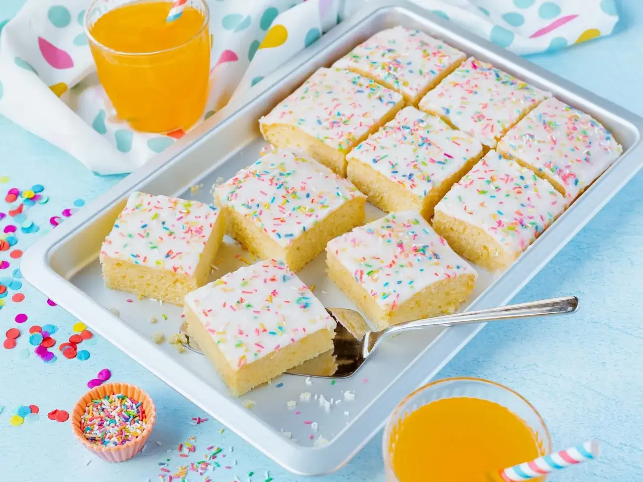 Bunter Fantakuchen, perfekt f&uuml;r ein Fantakuchen Rezept. Serviert auf einem Blech mit Streuseln und einem Glas Orangenlimonade.