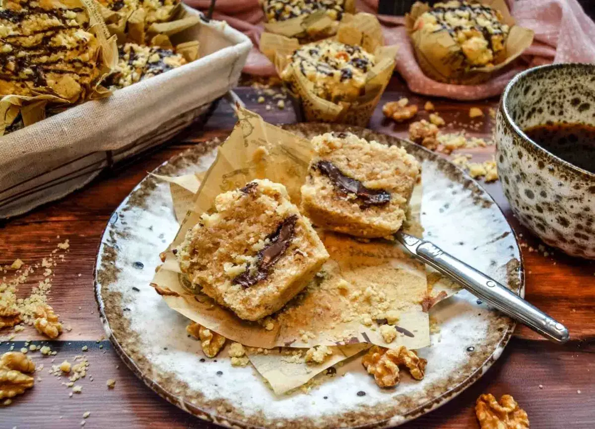 Saftige Nutella Muffins mit Streuseln und Schokost&uuml;ckchen, serviert auf einem Teller mit Waln&uuml;ssen und einer Tasse Kaffee.