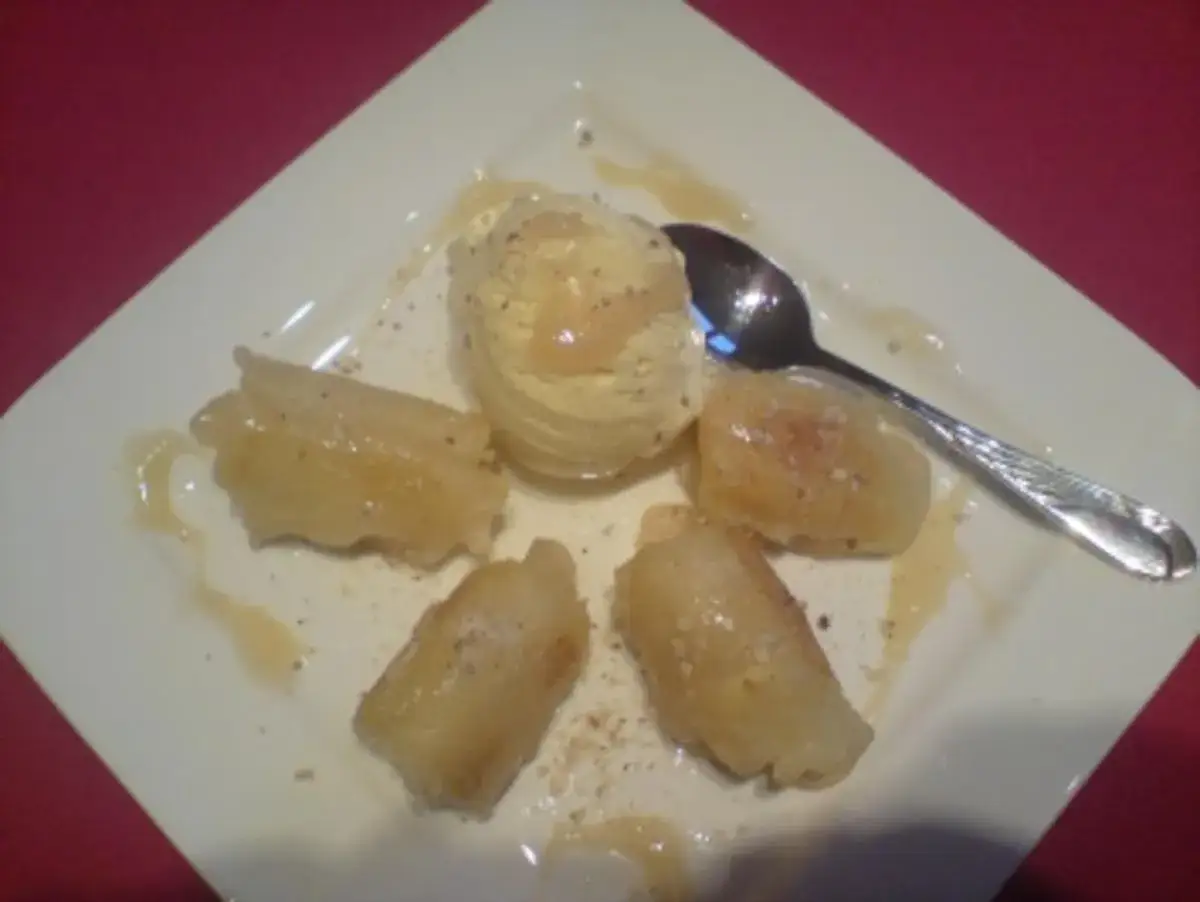 Gebackene Banane mit Vanilleeis und Sirup auf einem Teller.
