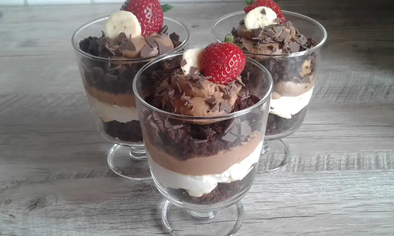 Schokoladen-Dessert im Glas: Schichten aus Schokokuchen, Creme und Mousse au Chocolat, garniert mit Erdbeeren und Bananen. Perfekt mit dem Thermomix zubereitet.