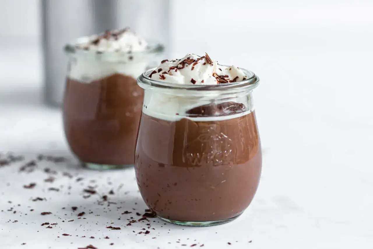 Zwei Gl&auml;ser mit cremigem Schokopudding, gekr&ouml;nt mit Schlagsahne und Schokostreuseln. Perfekt, um Schokopudding selber machen zu lernen!
