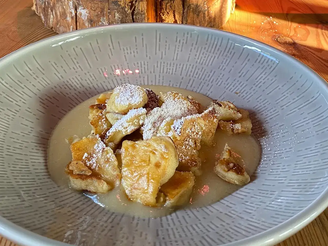 Ein köstlicher Kaiserschmarrn, frisch zubereitet nach einem einfachen Rezept, bestäubt mit Puderzucker und serviert in einer stilvollen Schüssel.