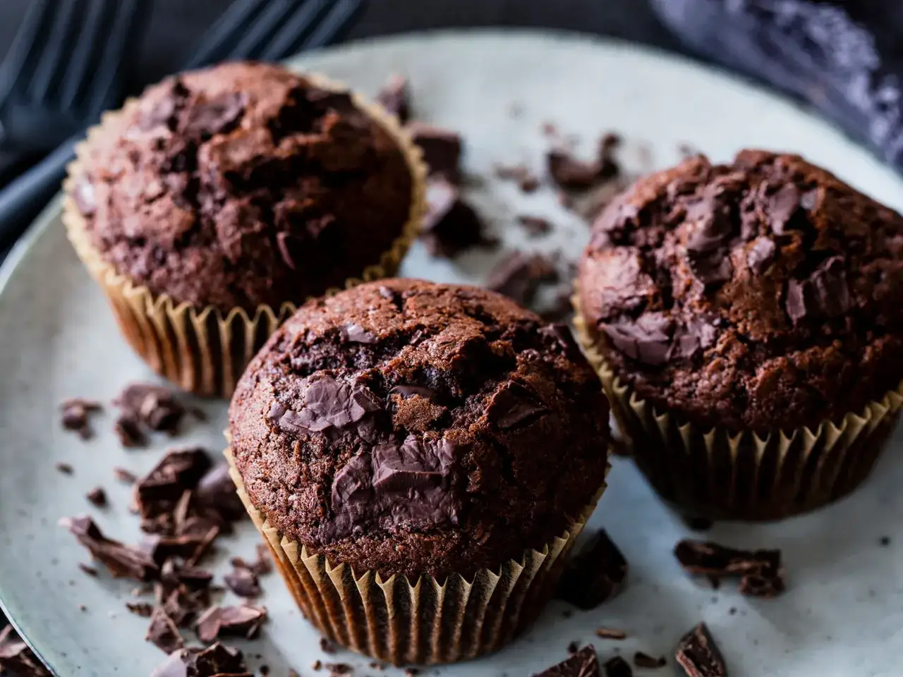 Drei saftige Schoko-Muffins mit Schokoladenstückchen, perfekt für ein schnelles Muffins Rezept.