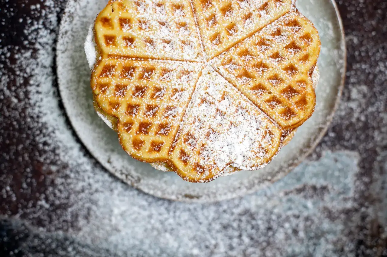 Herzförmige Bananenwaffeln, bestäubt mit Puderzucker, auf einem Teller. Ein süßer Genuss für jeden Tag.