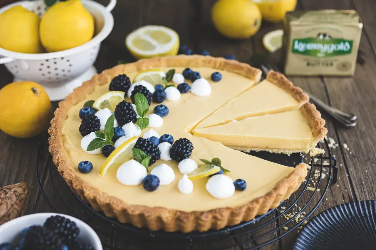 Zitronentarte rezept: Cremige Tarte mit frischen Beeren, Minze und Zitronenspalten. Ein Genuss f&uuml;r jeden Anlass!