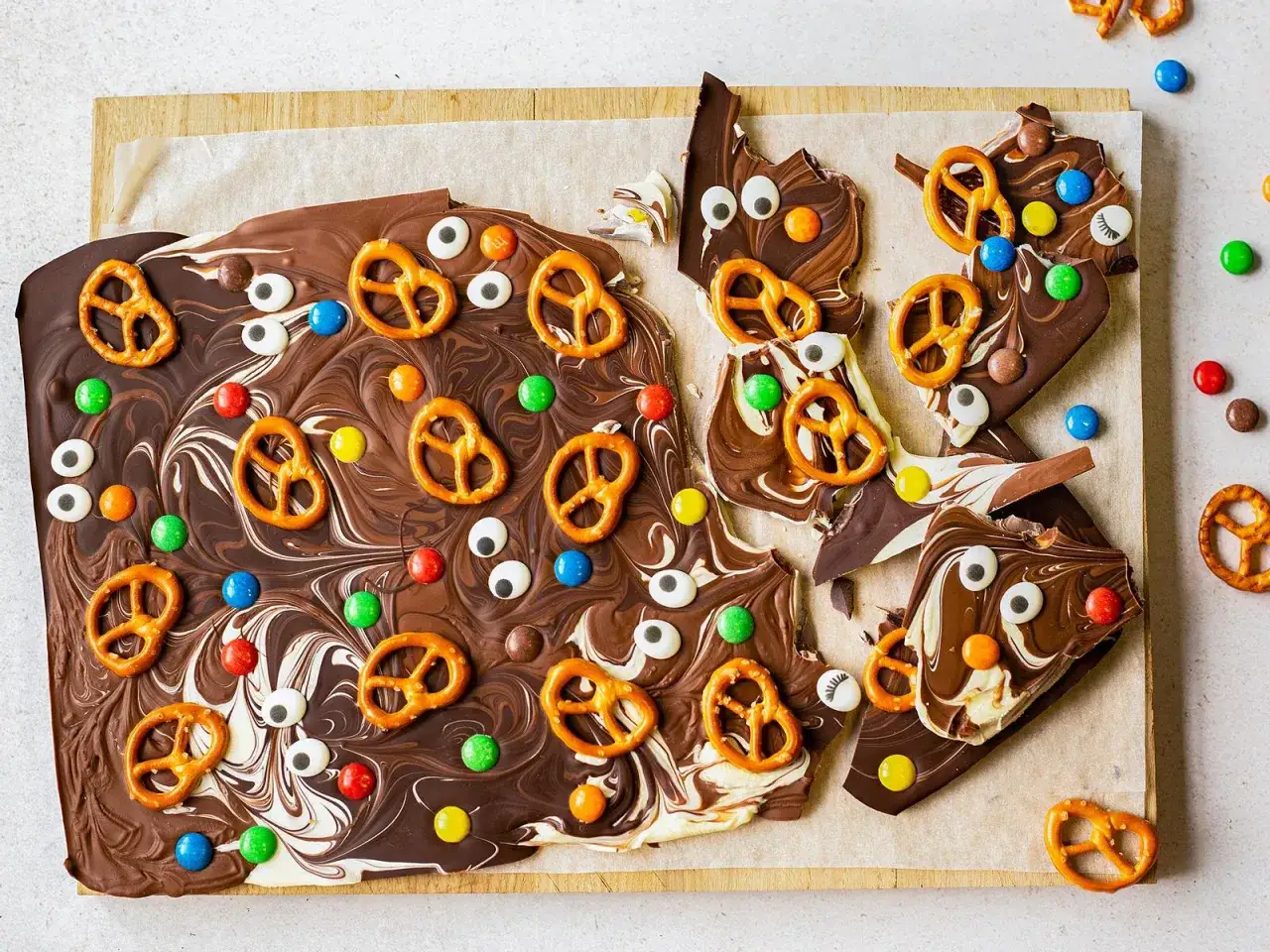 Bruchschokolade selber machen: bunte Smarties, Salzbrezeln und lustige Zuckeraugen zieren die geschwungene Schokoladenplatte. Ein süßer Genuss!