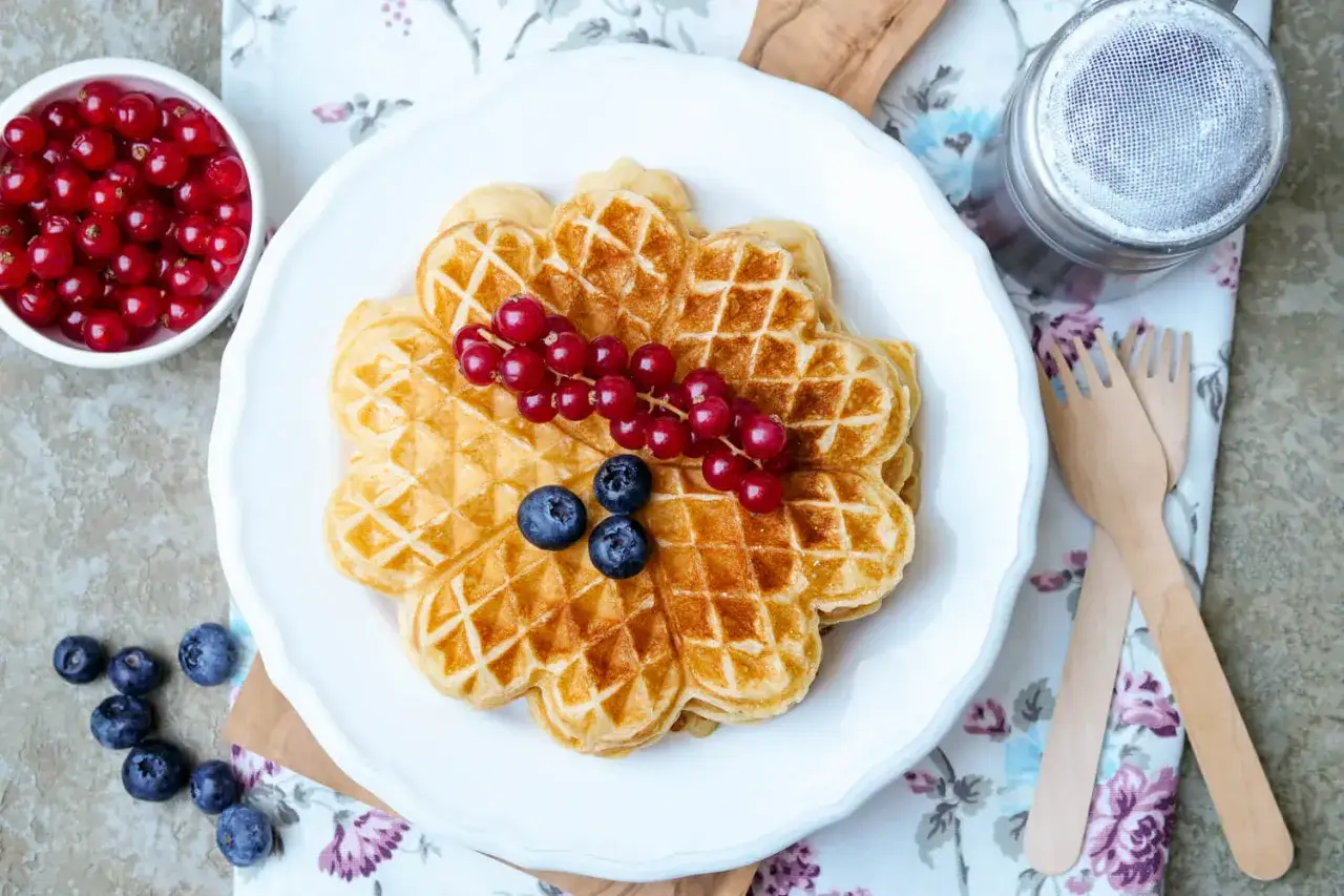 Herzhafte Quarkwaffeln mit roten Johannisbeeren und Blaubeeren, perfekt für ein leichtes Frühstück.