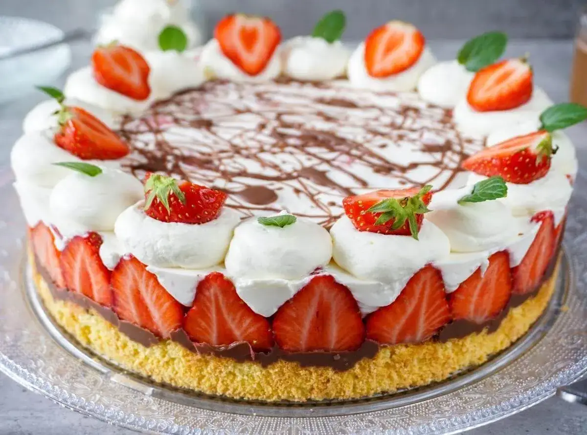 Eine köstliche Erdbeer Mascarpone Torte, verziert mit frischen Erdbeeren, Sahnetupfern und Schokoladensauce.