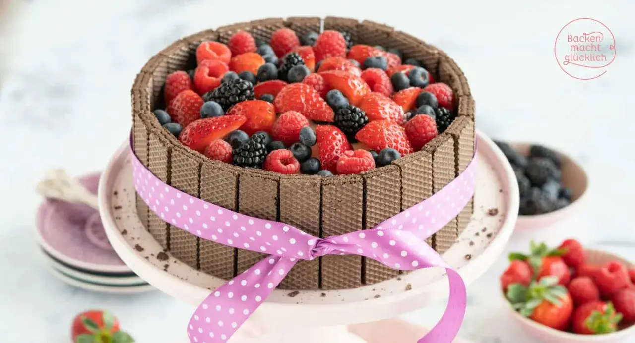 Eine köstliche Kinderschokolade Torte, umrandet von Waffelröllchen und üppig belegt mit frischen Beeren und Erdbeeren.