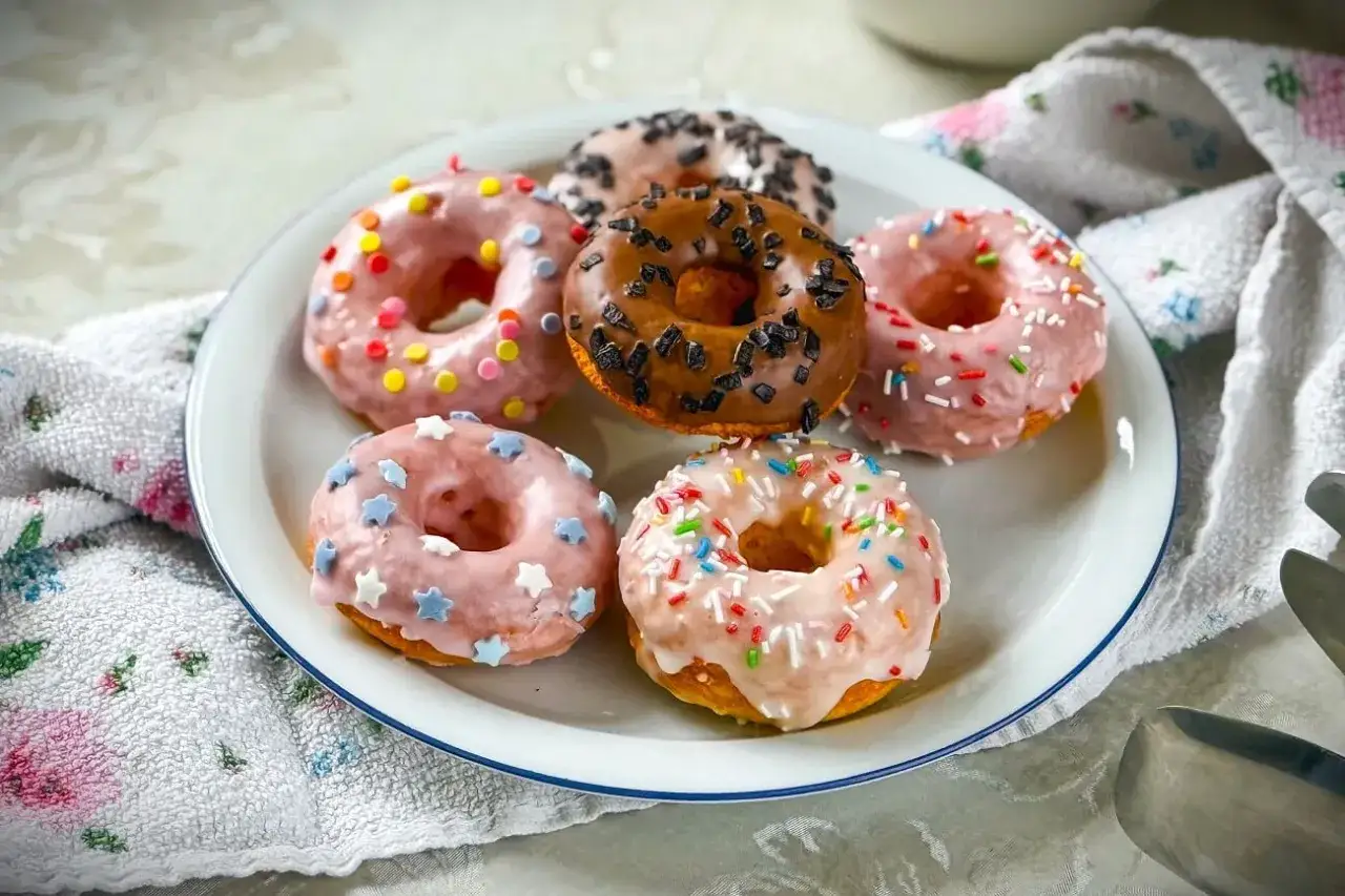 Sechs bunte Donuts mit Streuseln und Sternen auf einem Teller, ein k&ouml;stliches Donuts Rezept zum Nachbacken.