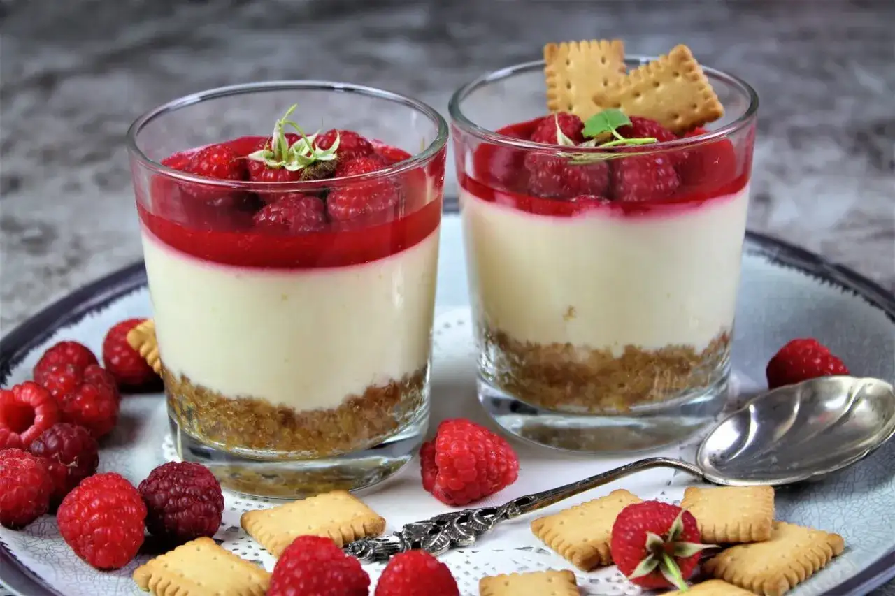 Zwei leckere Desserts im Glas mit Himbeeren und Keksen, ein süßer Genuss.