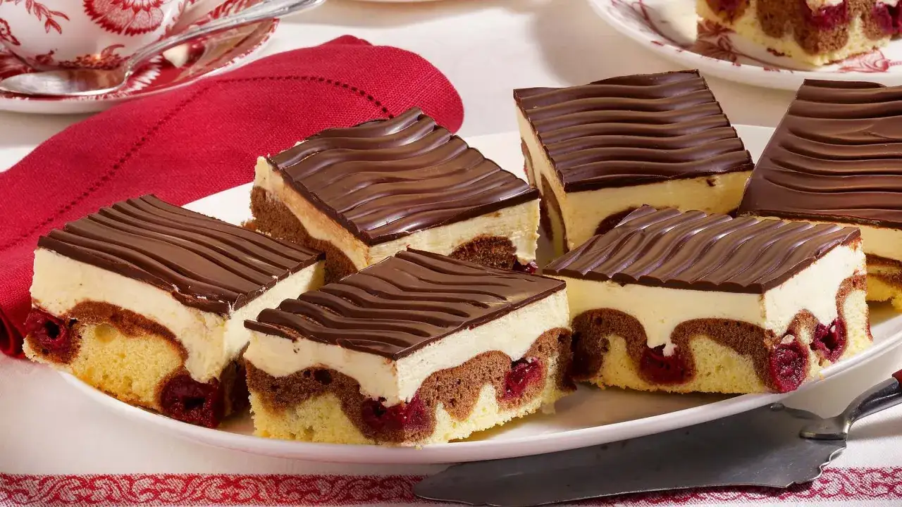 St&uuml;ckchen einer k&ouml;stlichen Donauwelle, mit Kirschen, hellem und dunklem Teig, Vanillecreme und Schokoladenguss.