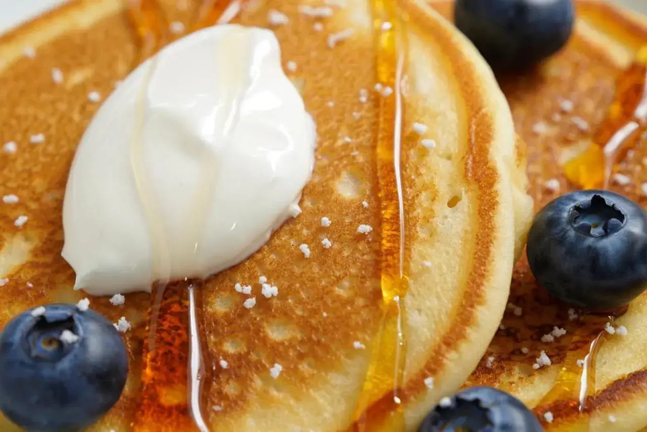 Fluffige Pancakes mit Kefir, garniert mit Honig, Blaubeeren und einem Klecks Sahne. Ein Genuss f&uuml;r jeden Morgen!