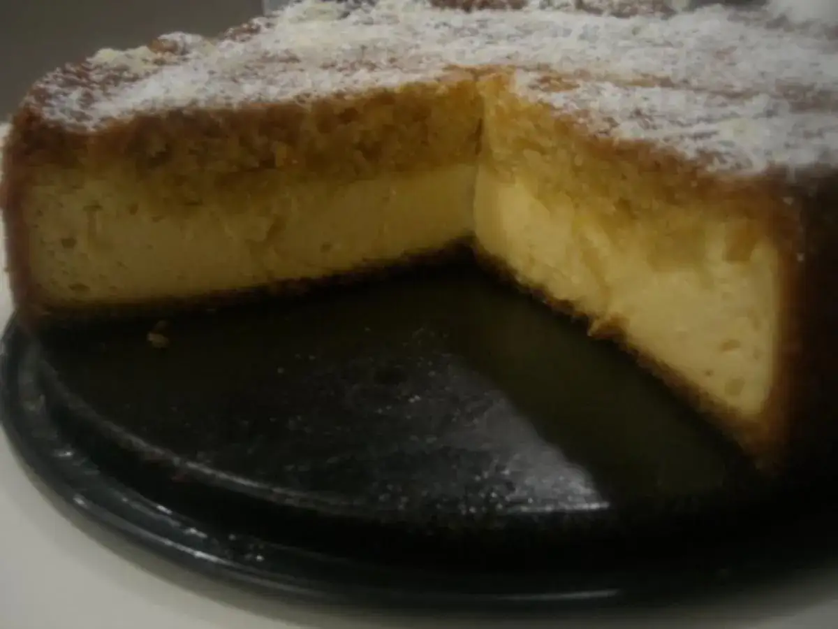 Ein cremiger Käsekuchen mit knusprigem Boden, bestäubt mit Puderzucker. Dreh dich um, Kuchen, du siehst köstlich aus!