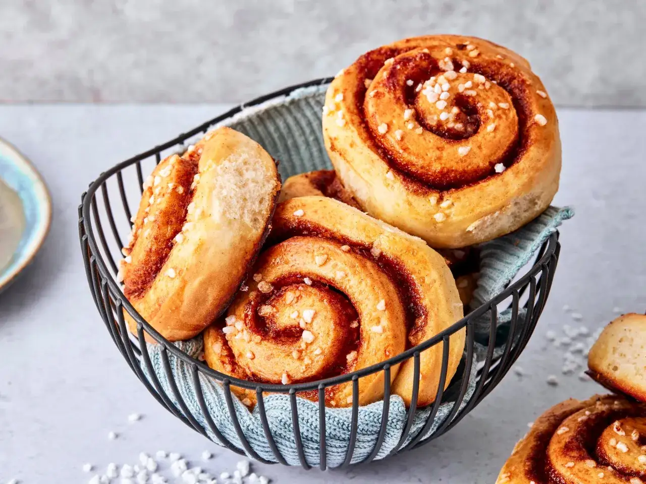 Korb mit frisch gebackenen schwedischen Zimtschnecken, bestreut mit Zuckerperlen.