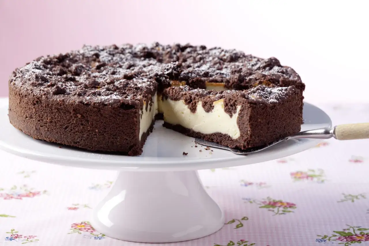 Ein saftiger russischer Zupfkuchen mit Schokoladenstreuseln und cremiger Füllung, bestäubt mit Puderzucker.