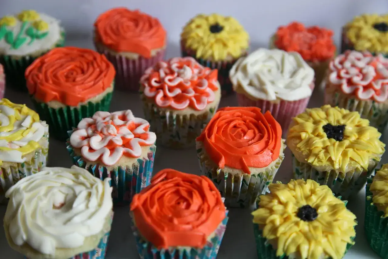 Bunte Cupcakes mit Buttercreme-Verzierungen, die wie Blumen aussehen. Ein köstliches Buttercreme-Rezept für jeden Anlass.