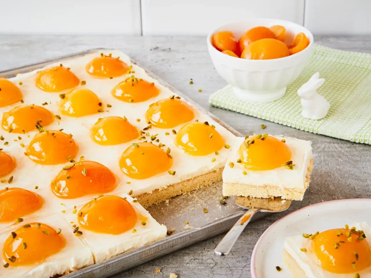Ein saftiger Kuchen mit einer cremigen Schicht und leuchtenden Aprikosenhälften, bestreut mit gehackten Pistazien. Dieser Spiegelei Kuchen ist ein wahrer Genuss.