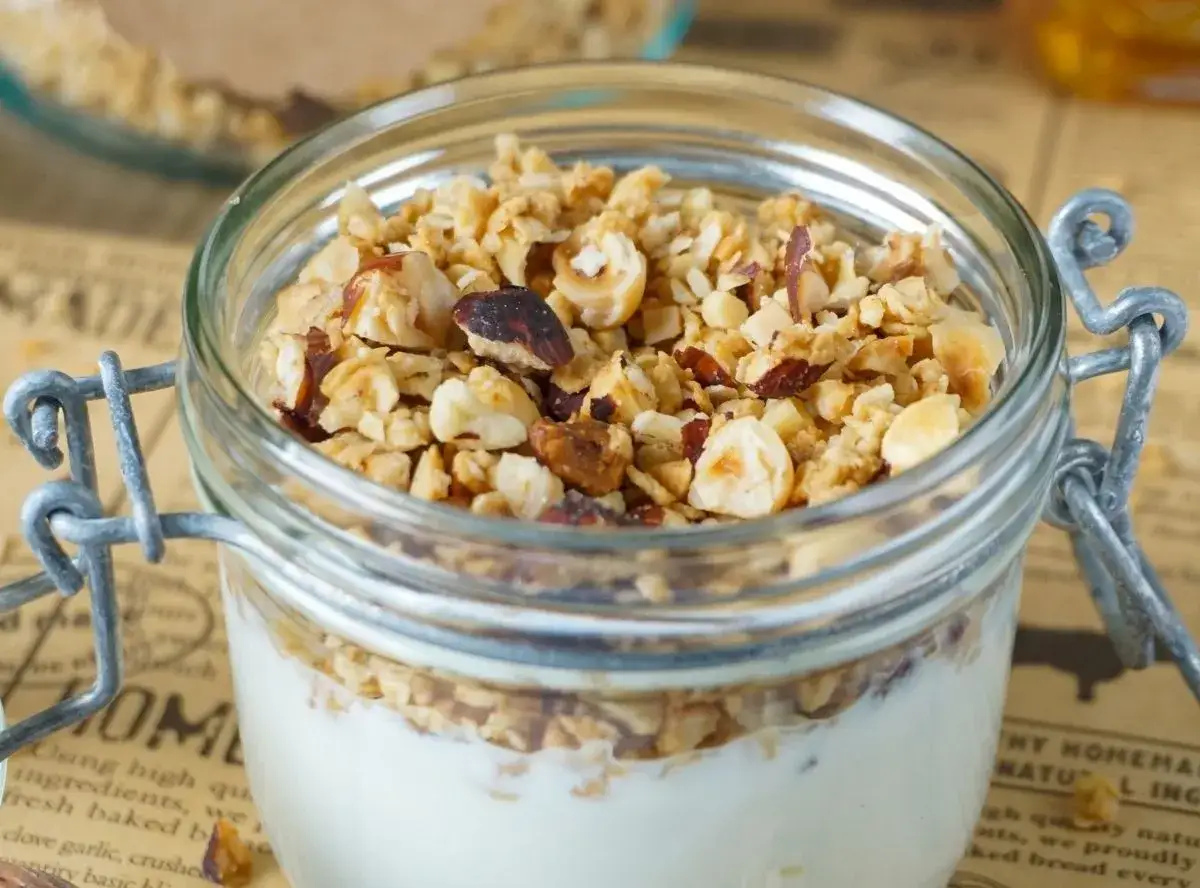 Ein Glas mit Joghurt und selbstgemachtem Granola, das mit N&uuml;ssen verfeinert ist. Perfekt f&uuml;r ein gesundes Fr&uuml;hst&uuml;ck.