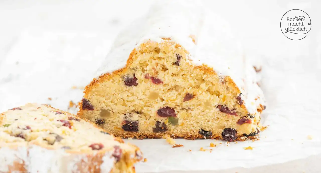 Ein Anschnitt eines traditionellen Stollen mit Puderzucker bestäubt. Das Stollen Rezept ist sichtbar mit vielen Rosinen und kandierten Früchten.
