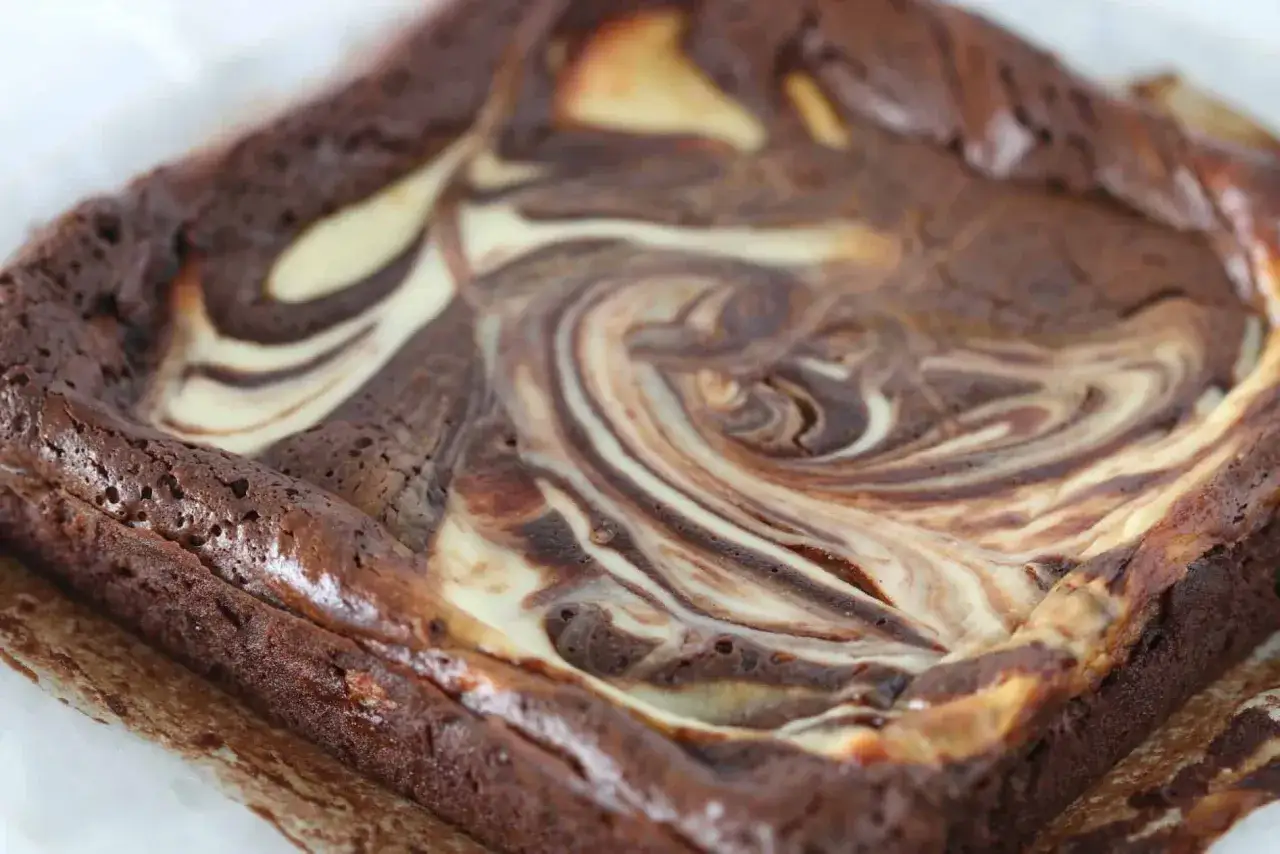 Ein Quadrat aus saftigen Cheesecake Brownies mit wirbelnden Schokoladen- und Frischk&auml;se-Mustern.