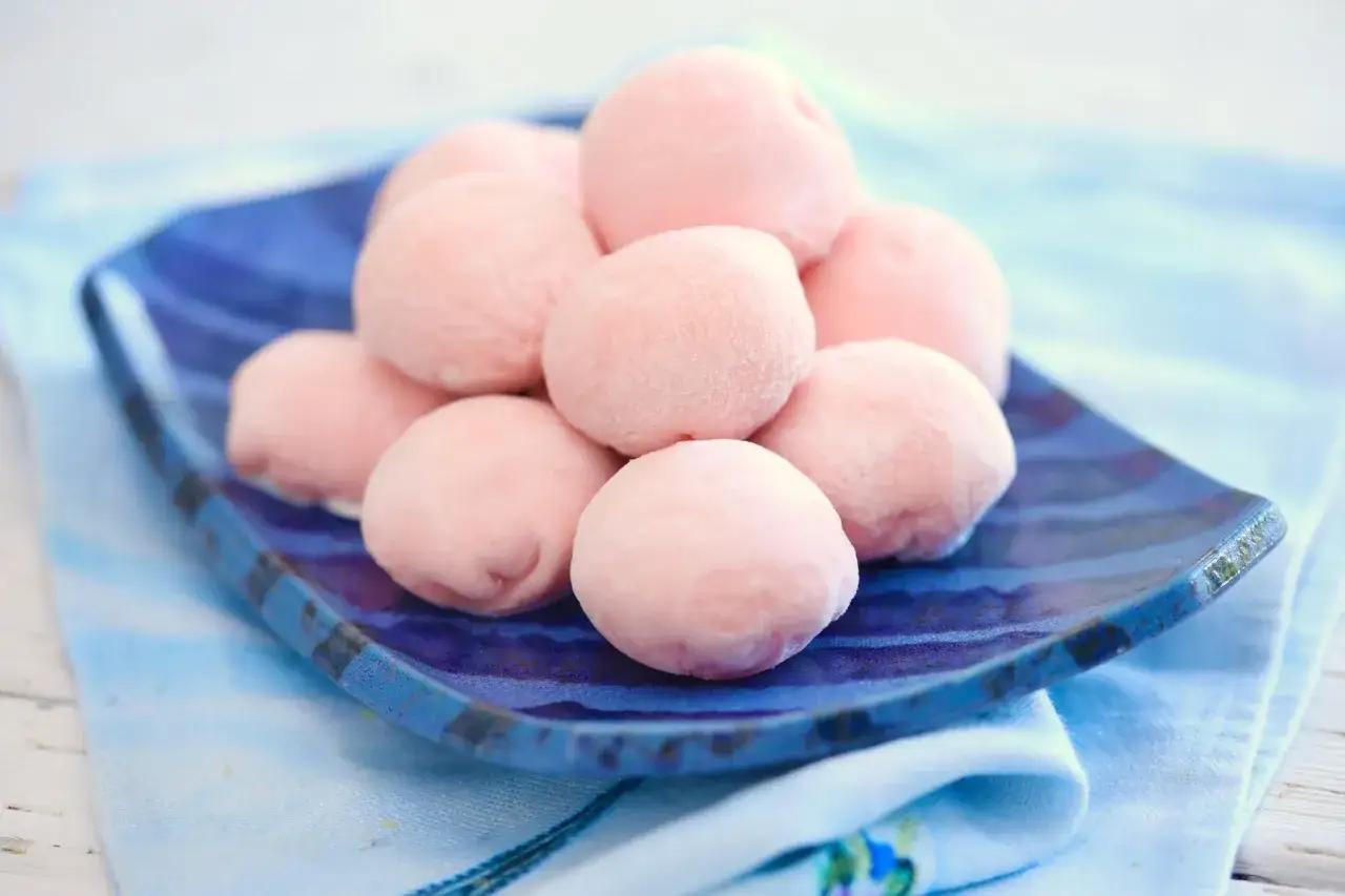 Zuckersüße, rosafarbene Mochi-Bällchen auf einer blauen Platte. Perfekt zum Mochis selber machen und Genießen.