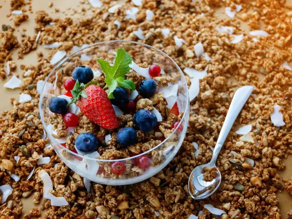 Schüssel mit frischem Granola, Beeren und Kokosflocken. Perfekt für ein gesundes Frühstück, wenn du Granola selber machen möchtest.