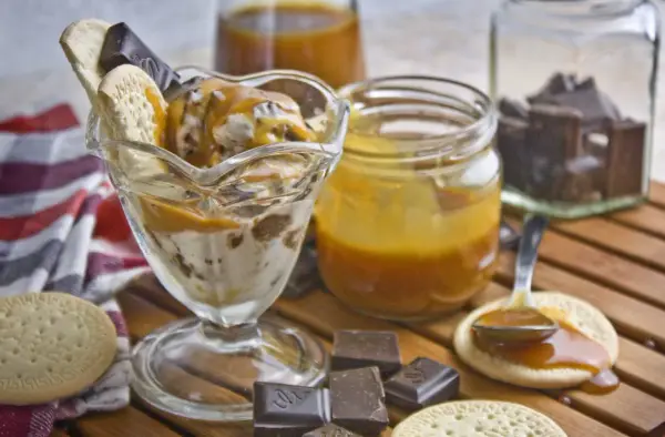 Eisbecher mit Karamellsauce, Keksen und Schokostückchen. Selbstgemachtes Karamell zum Verfeinern.